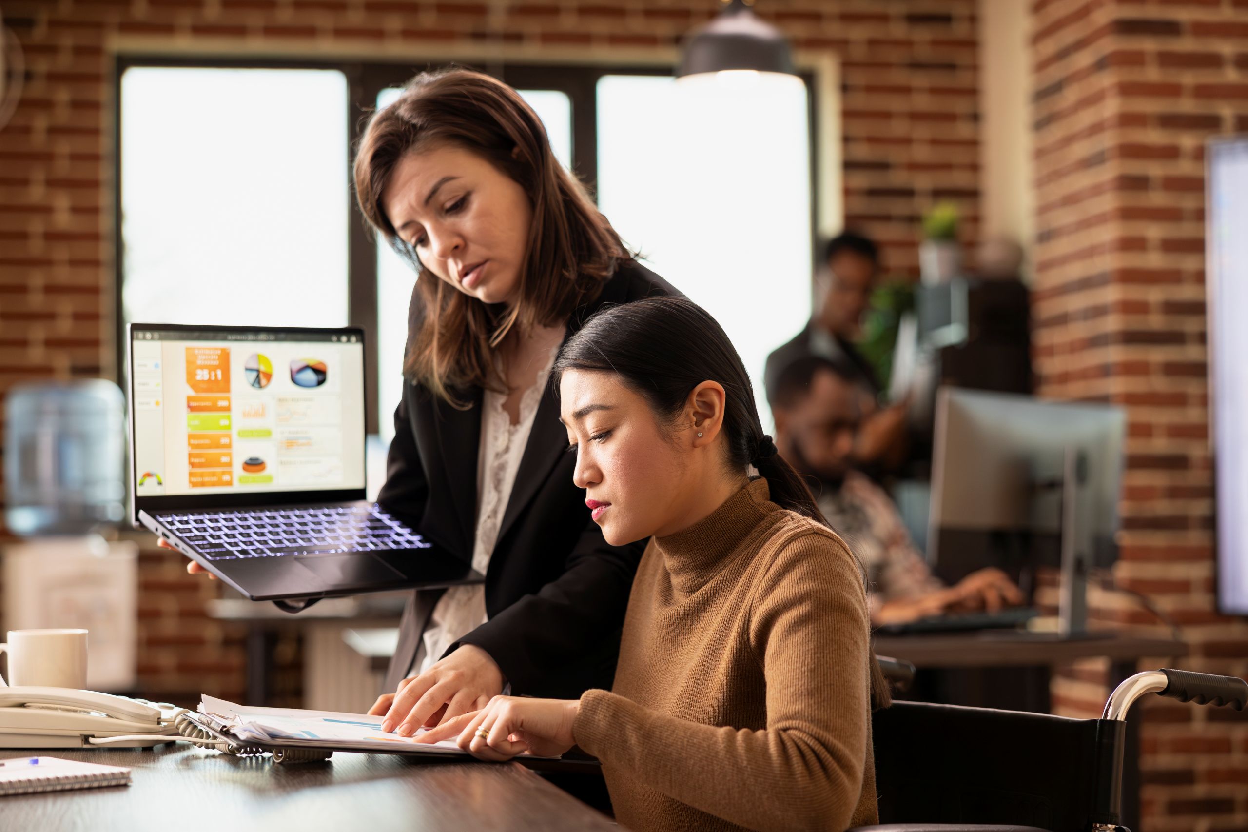 Two women collaborating on documents in a modern office. Two women collaborating on documents in a modern office.